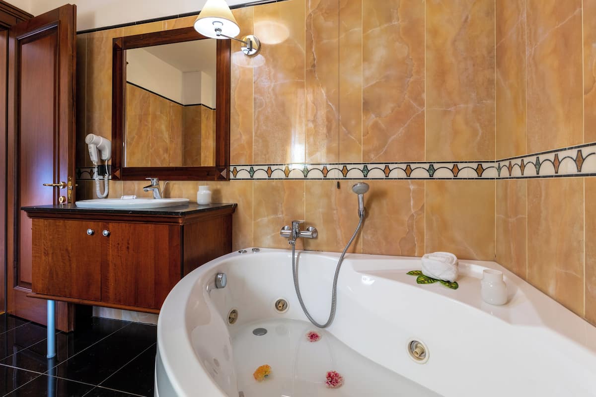 Une salle de bain avec une baignoire, un lavabo, un miroir et un meuble-lavabo.