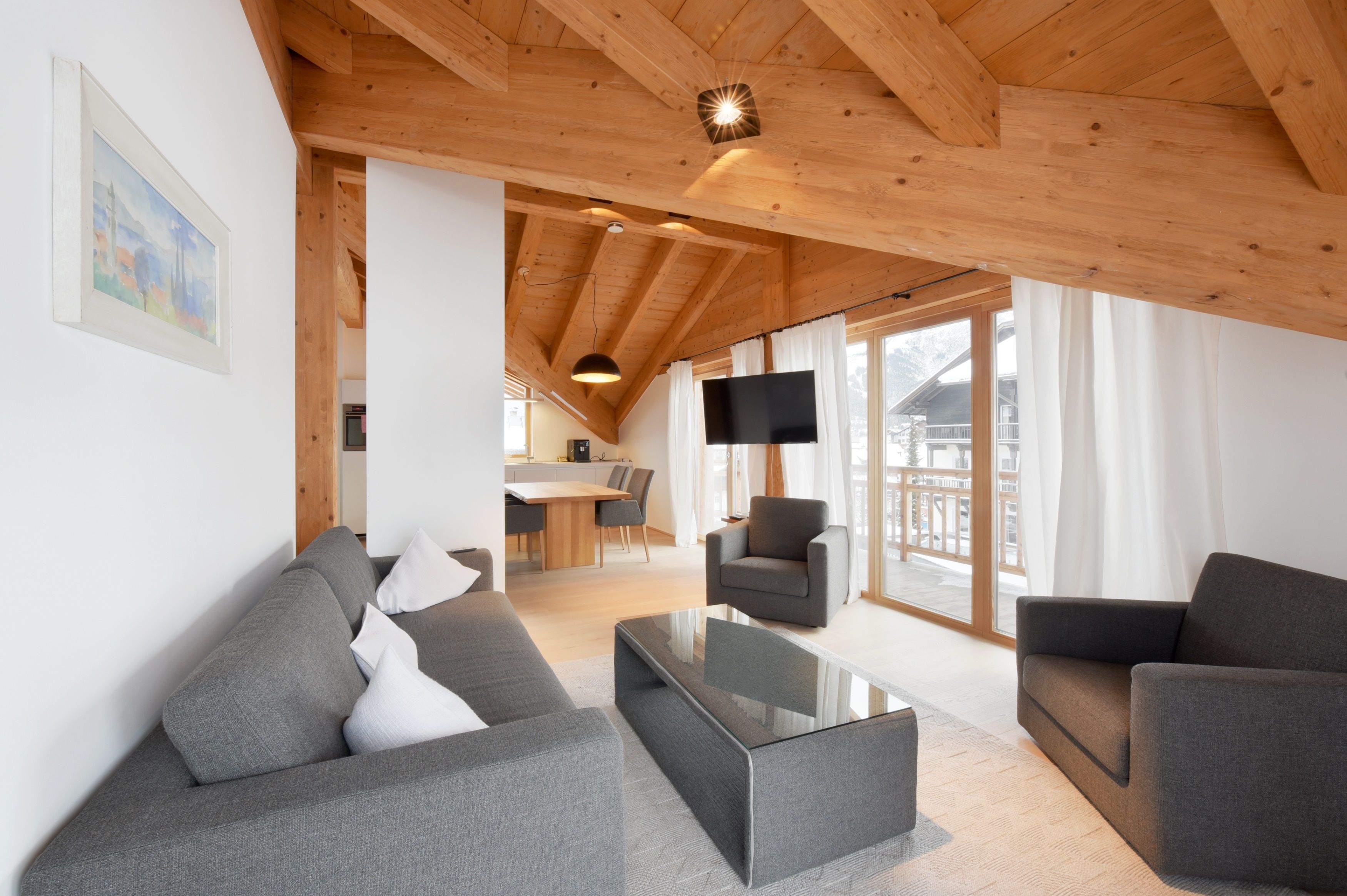 A modern living room with a wooden ceiling, a flat-screen TV, and a dining area in the background.