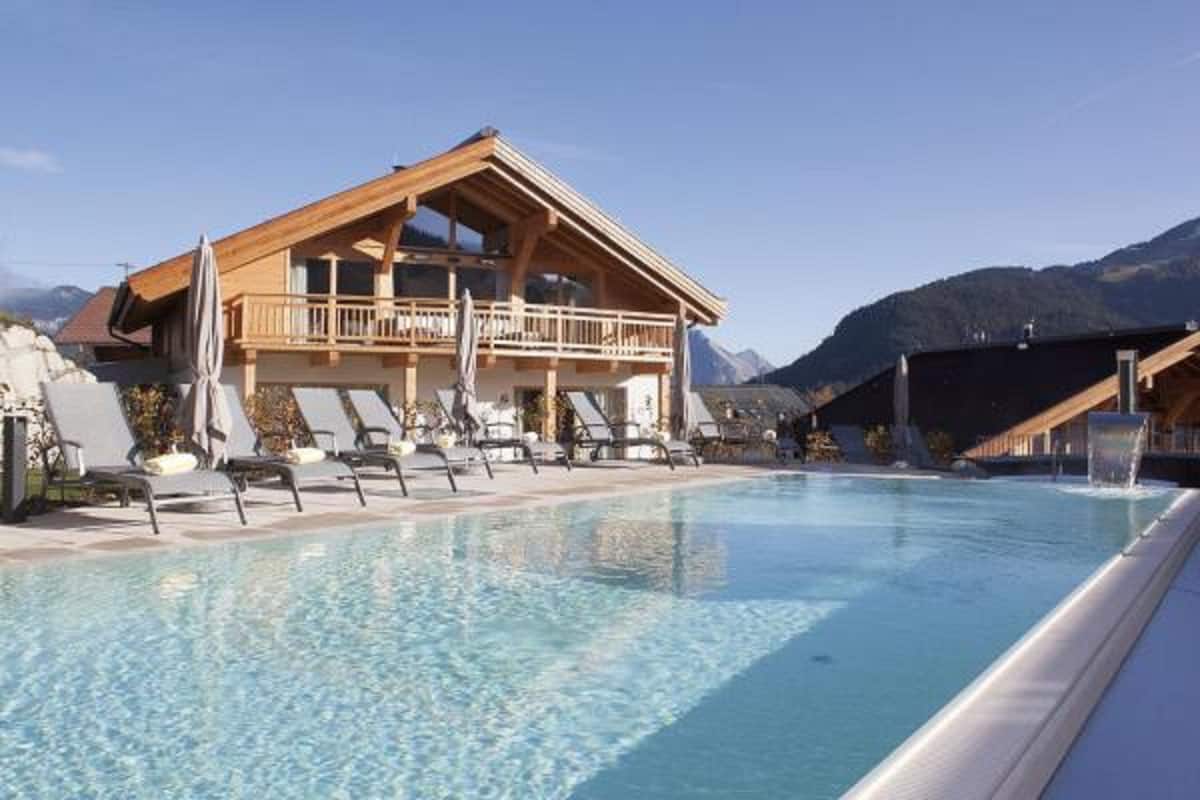 A hotel with a pool, lounge chairs, and mountain views.
