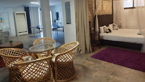 A hotel room with a bed, a dining table, wicker chairs, a purple rug, and a view of the dining area. - House / Villa - LAS GALLETAS (LAS GALLETAS)