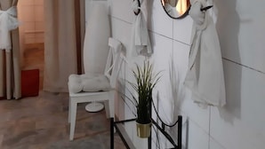 A spa room with a white chair, a small table with a plant, and a mirror on the wall. - House / Villa - LAS GALLETAS (LAS GALLETAS)