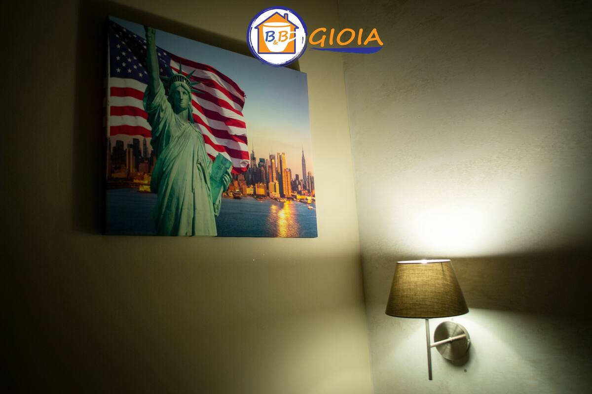 A wall with a painting of the Statue of Liberty and the American flag, a B&B logo, and a lamp.