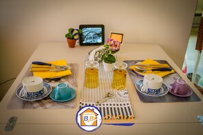 A table set with various cups, saucers, and napkins, along with a tablet and a small potted plant.
