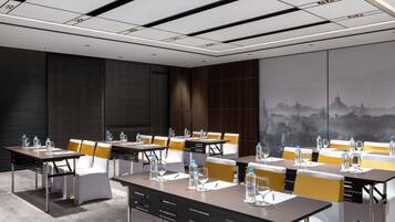 A conference room with tables, chairs, and a cityscape mural.