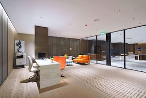 A modern office space with a marble desk, an orange sofa, and a glass partition. - Wyndham Grand Yangon (Yangon)