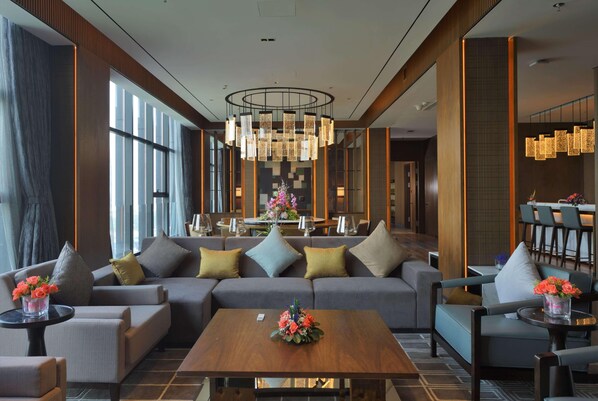 A modern hotel lobby with a large sofa, armchairs, a coffee table, and a dining area in the background. - Wyndham Grand Yangon (Yangon)
