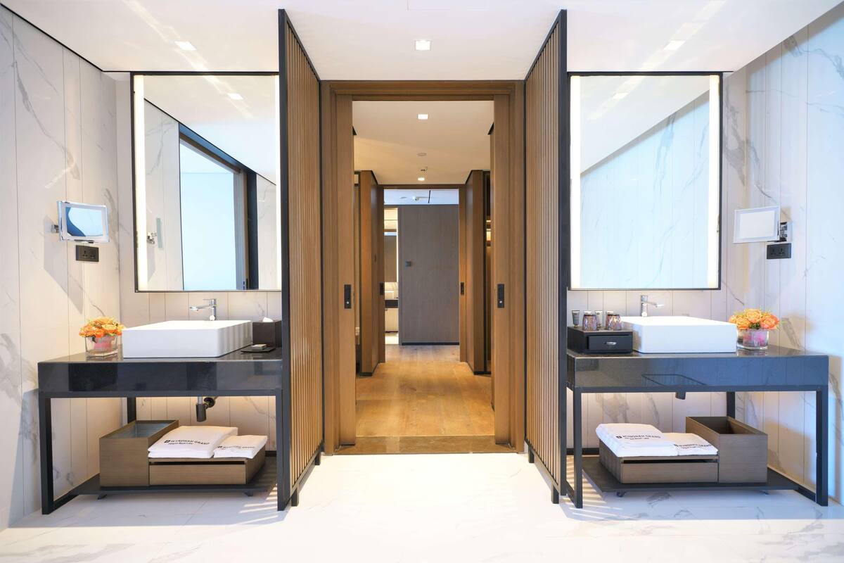 A modern bathroom with two sinks, a large mirror, and a wooden vanity.