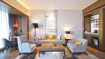 A modern living room with a sofa, two armchairs, a coffee table, and a large abstract painting on the wall.