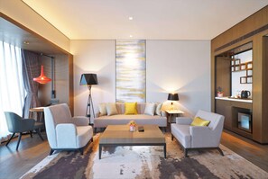 A modern living room with a sofa, two armchairs, a coffee table, and a large abstract painting on the wall. - Wyndham Grand Yangon (Yangon)
