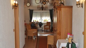 A dining area with wicker chairs, a wooden cabinet, and a table with a white tablecloth. - Bei Hölzchen (Hannover)