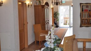 A hallway with wooden doors, a wicker chair, a table, and a vase with flowers. - Bei Hölzchen (Hannover)