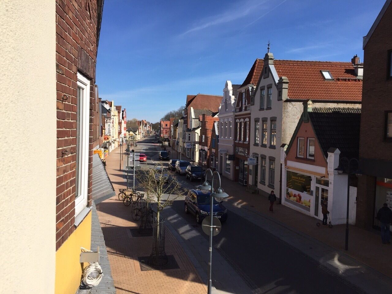 A street view with buildings, parked cars, and a clear sky.