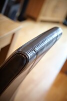 Primer plano de un reposabrazos de cuero con detalles de costura.