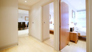 A hotel room with a wooden floor, a bed, a bedside table, and a wardrobe. - Pelican House (Newbury)