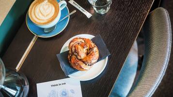 A table with a coffee cup, a pastry, a glass of water, and a napkin.