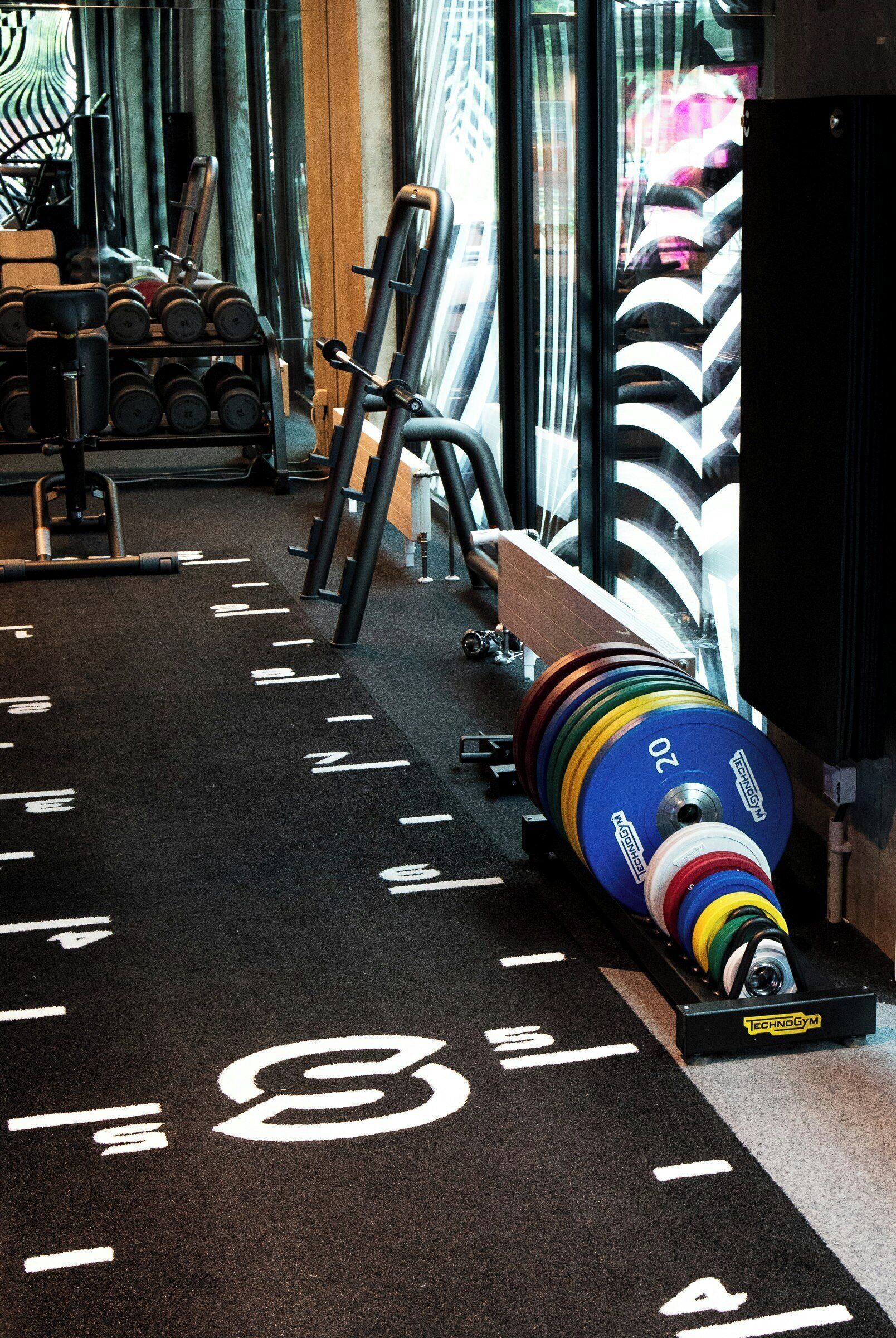 A gym with weightlifting equipment, a weight stack, and a mirrored wall.