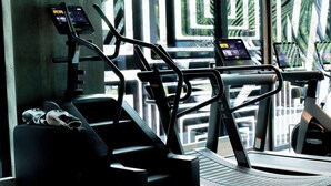 A gym with treadmills and a stationary bike, with a concrete wall and windows in the background. - The Social Hub Berlin (Berlin)