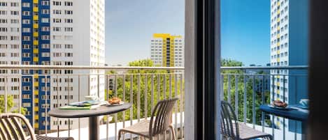 A balcony with a table, chairs, and a view of high-rise buildings.