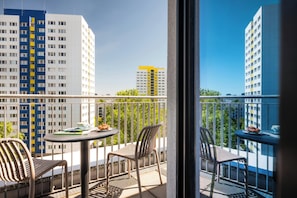 Un balcón con una mesa, sillas y vistas de edificios altos.