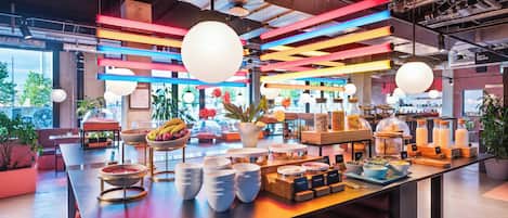 A modern dining area with a long table, multiple bowls, and a variety of food items.