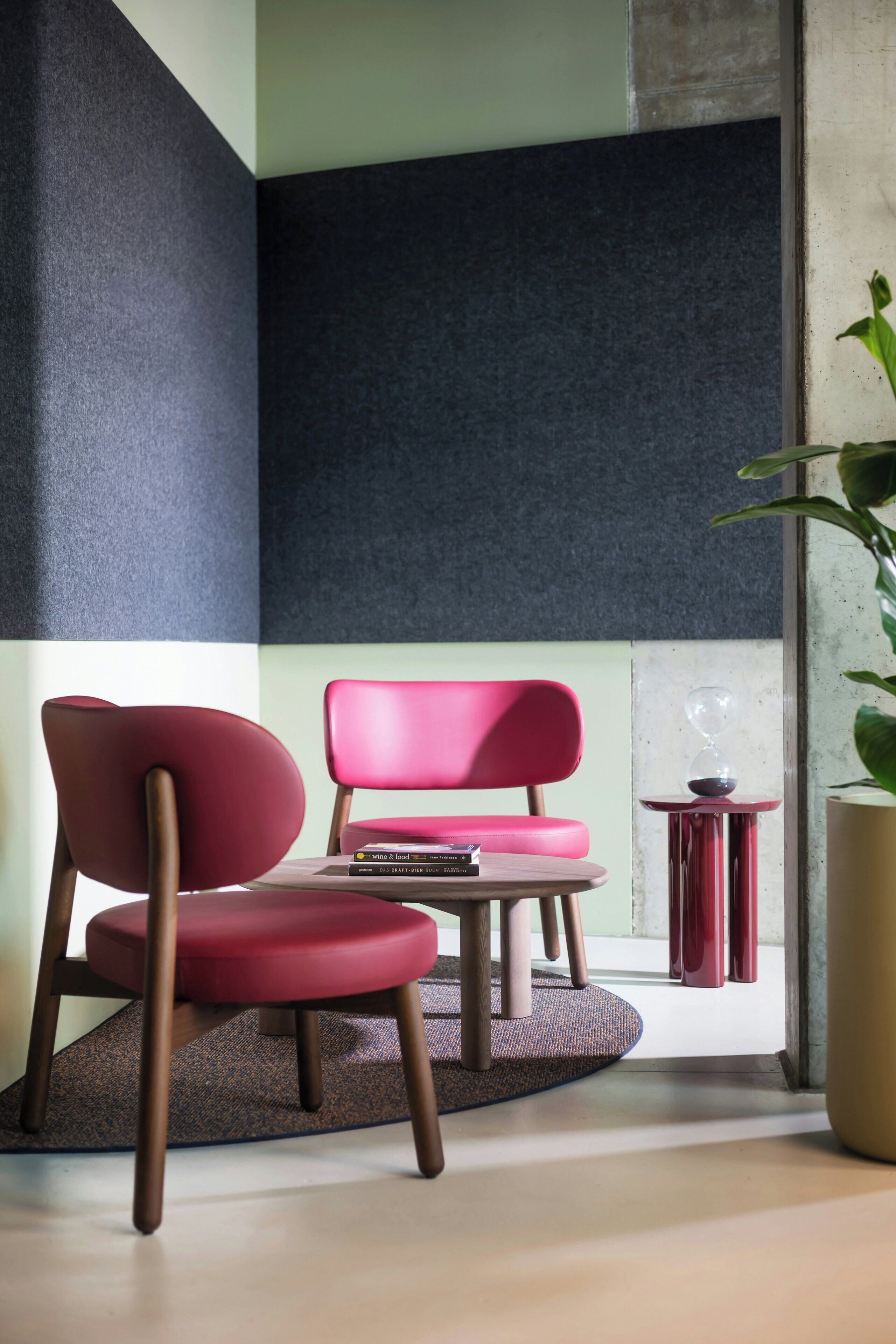A modern room with a red chair, a small table, and a potted plant.