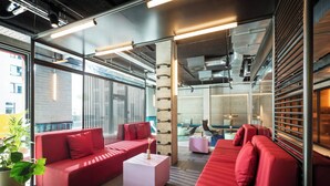 A modern interior with red sofas, a coffee table, and a potted plant. - The Social Hub Berlin (Berlin)