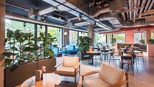 A modern interior with seating areas, tables, and potted plants. - The Social Hub Berlin (Berlin)