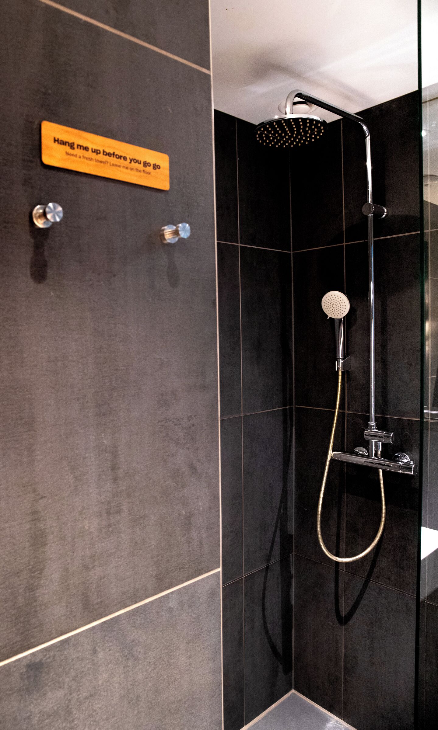 Ein modernes Badezimmer mit Dusche, Handtuchhalter und einem Schild mit der Aufschrift 'Vor dem Verlassen aufhängen'.