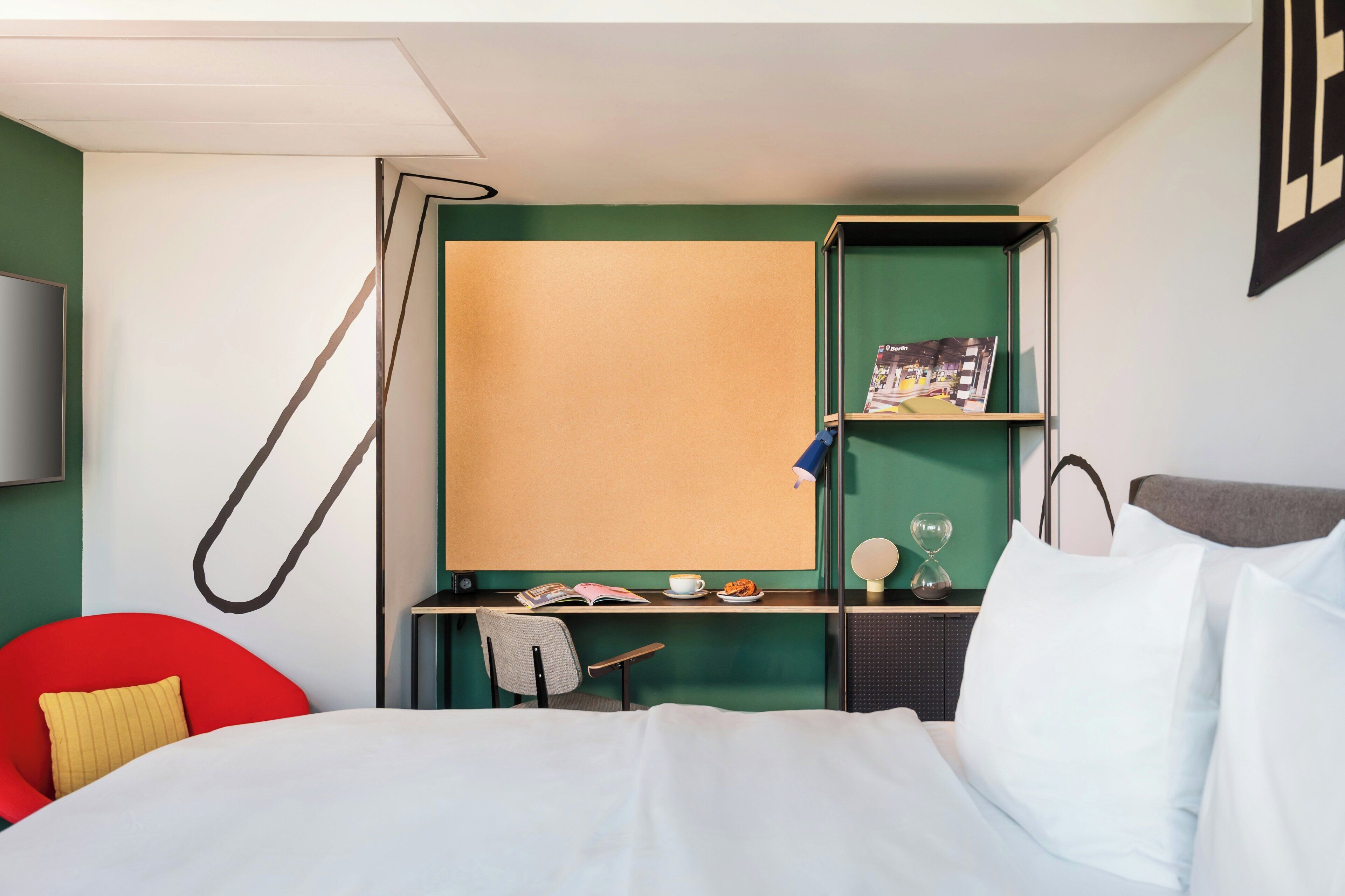 Ett hotellrum med en säng, ett skrivbord, en stol, en tv och en bokhylla.