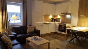Un espace de vie compact comprenant un coin cuisine, un coin repas et un espace détente avec un canapé et une table basse.
