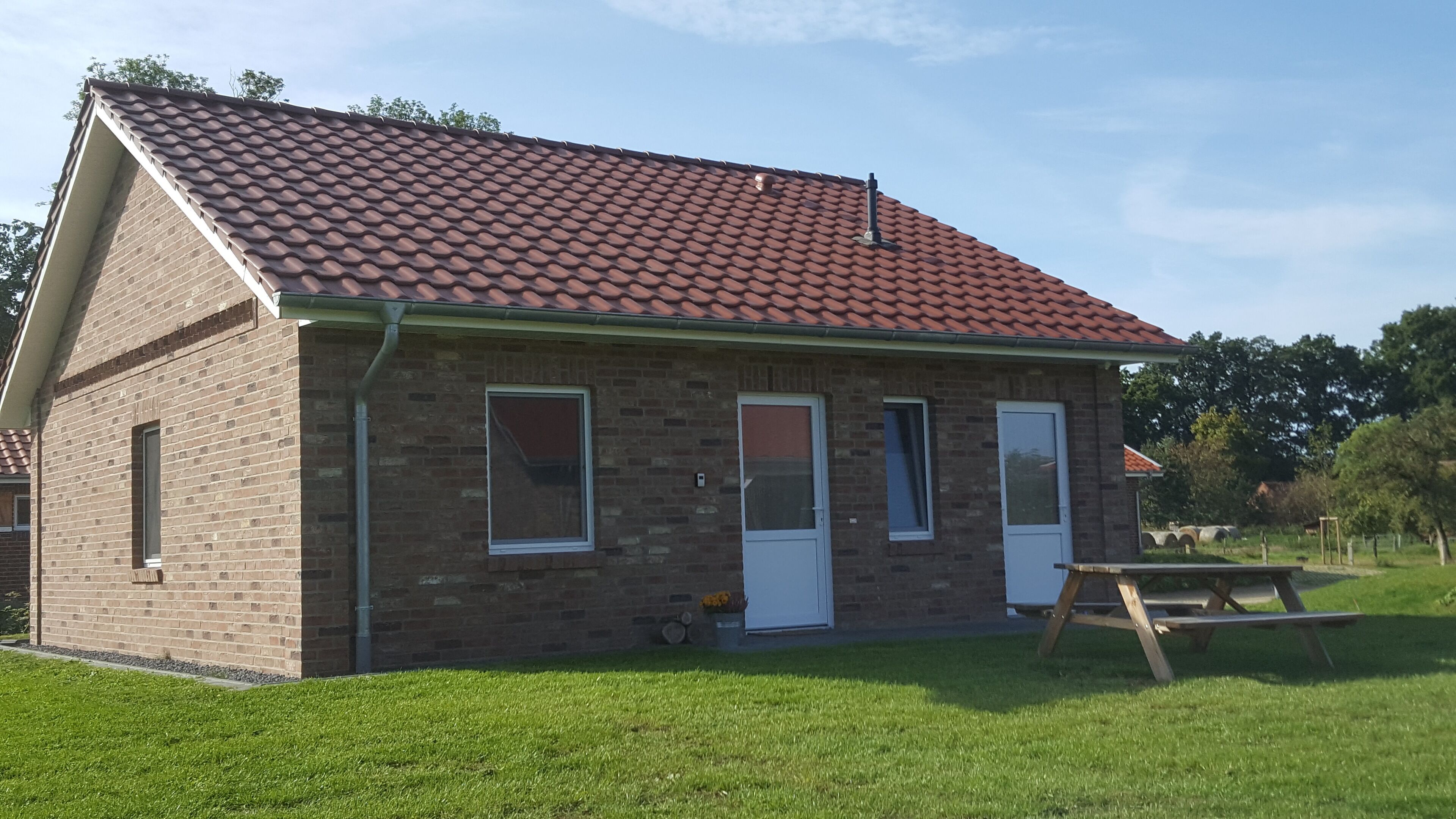 A brick house with a red-tiled roof, two doors, and windows.