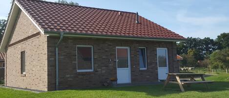 A brick house with a red-tiled roof, two doors, and windows.