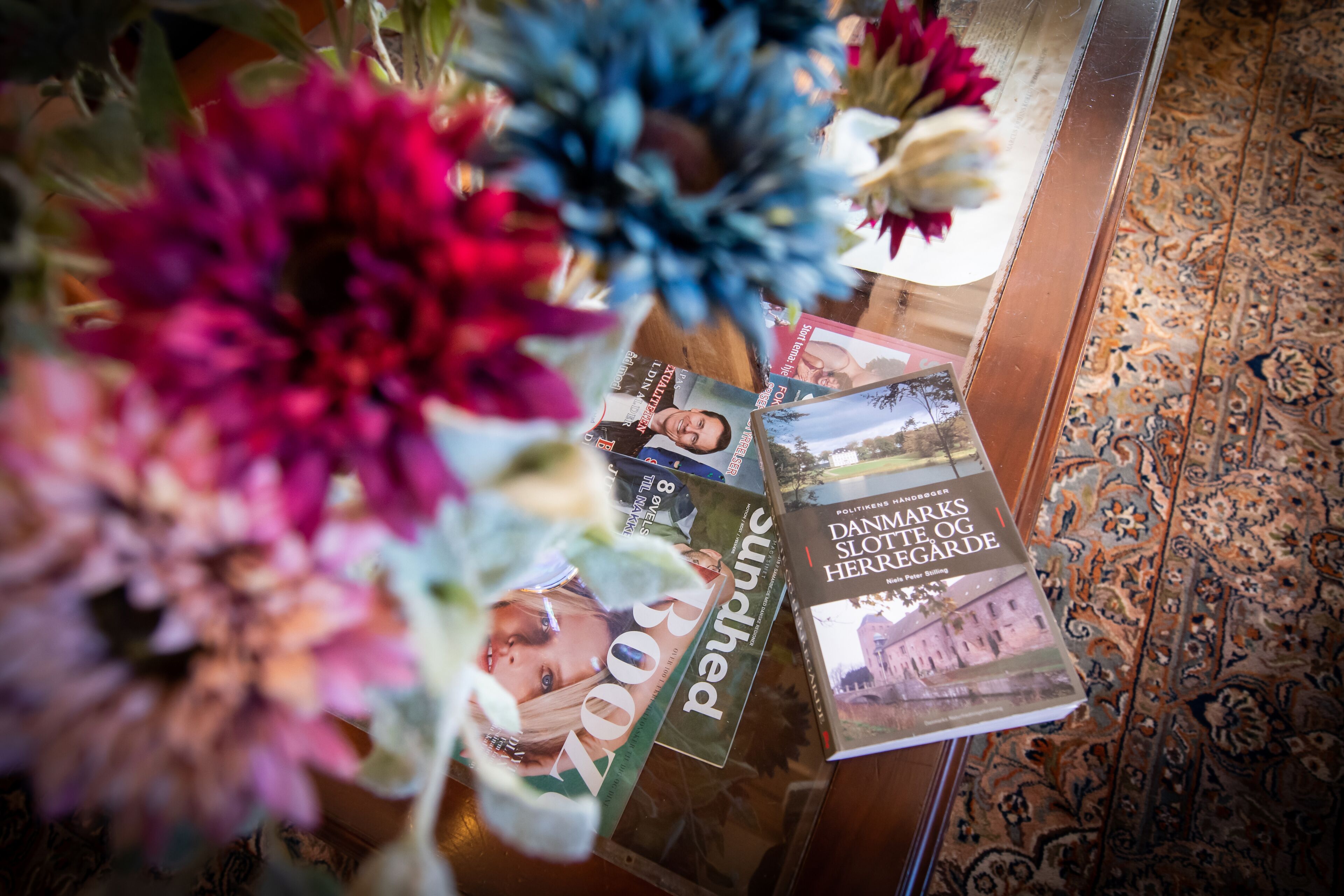 A table with magazines and a book titled "DANMARKS SLOTTE OG HERRIGARDE".