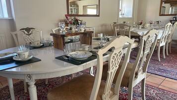 A dining area with white furniture, a wooden table, and a mirror on the wall.