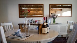 Una mesa de comedor dispuesta con botellas de vino, copas y un jarrón con flores.