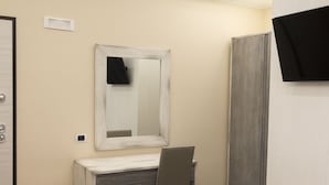 Een badkamer met een houten wastafelmeubel, een spiegel, een kast en een zwarte handdoek aan de muur.