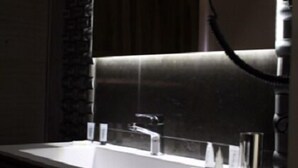 Een badkamer met een grote spiegel, een wastafel en een douchehoek.