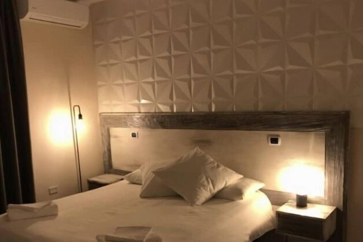 Ein Hotelzimmer mit einem Bett, Nachttischen und einer Wand mit geometrischem Muster.