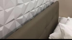 Een kamer met een muur met een geometrisch patroon en een bruin hoofdeinde.