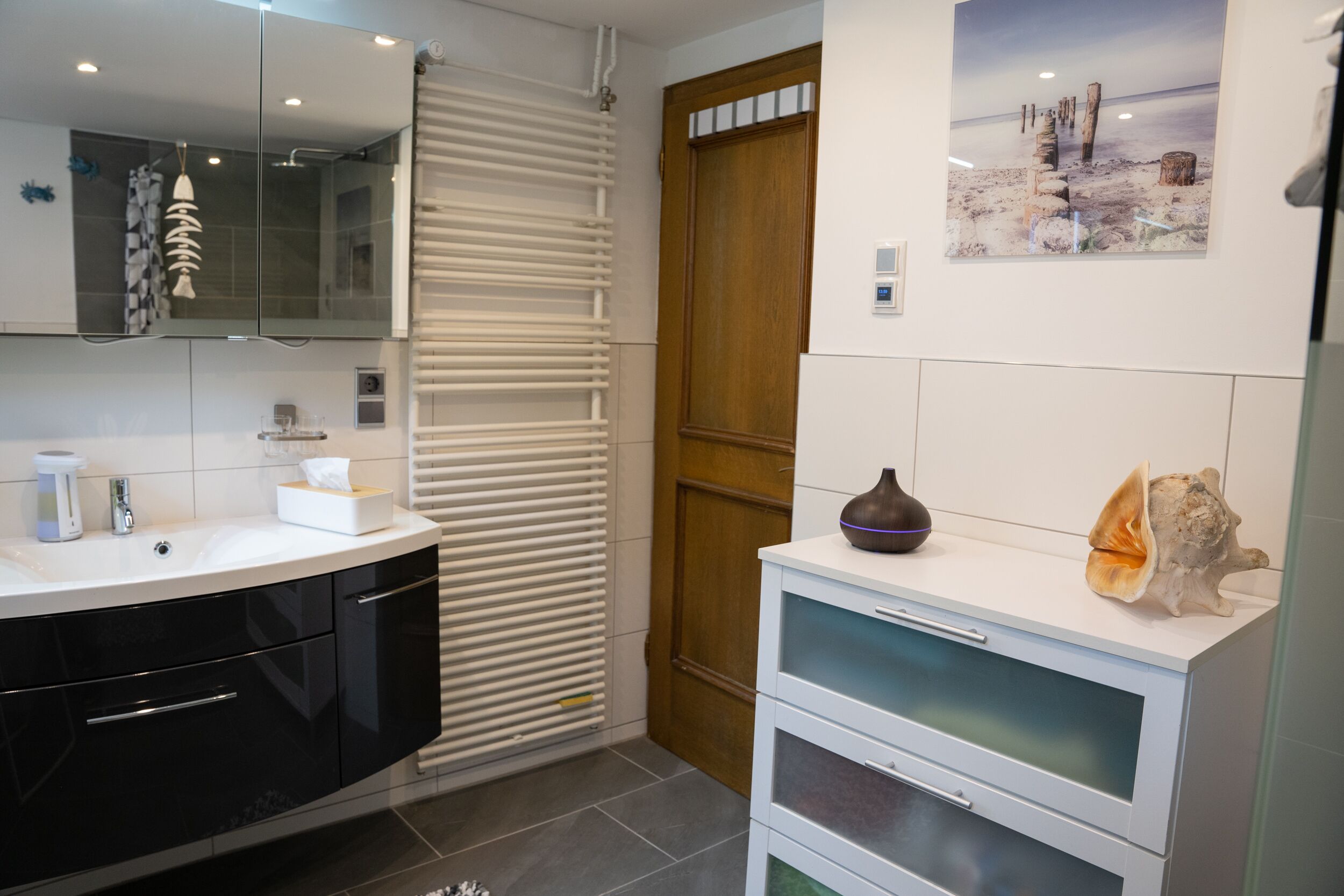 A modern bathroom with a black vanity, a glass shower enclosure, and a wooden door.