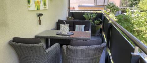 A balcony with wicker furniture, a table, and a lantern.