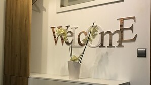 A reception desk with a 'Welcome' sign, a potted plant, and a mirror above.
