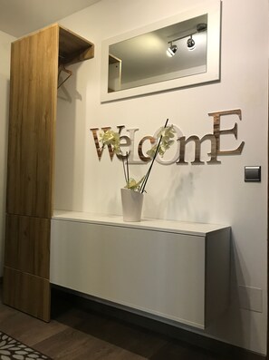 A reception desk with a 'Welcome' sign, a potted plant, and a mirror above.