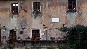 Ein rustikales Gebäude mit mehreren Fenstern, von denen einige mit Blumenkästen versehen sind. Ein Schild an der Fassade zeigt 