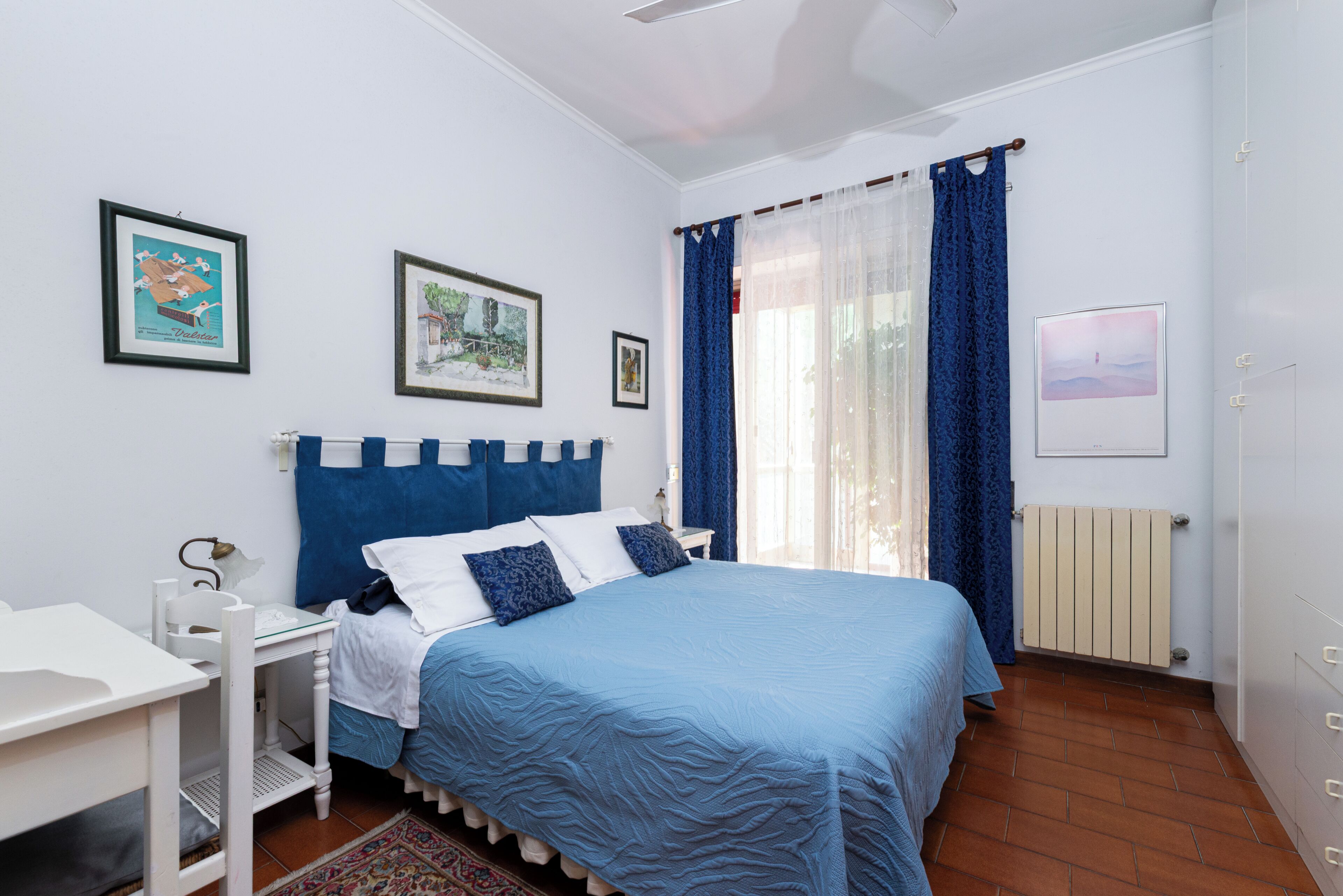 Un dormitorio con cama, escritorio y radiador.