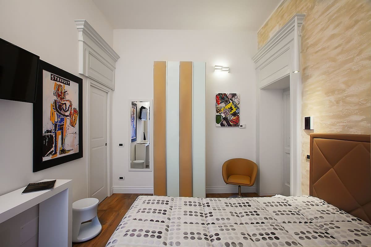 A bedroom with a bed, a chair, a toilet, and a mirror.