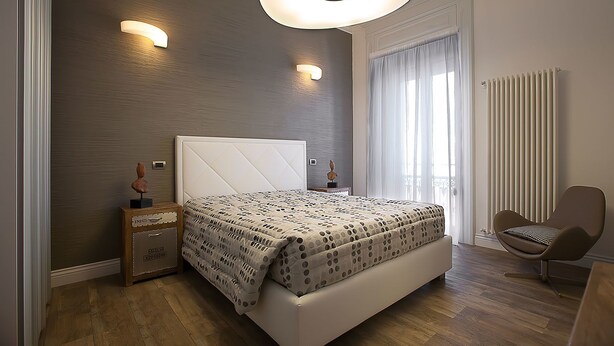 Un dormitorio moderno con una cama grande, una mesita de noche, una silla y un radiador.