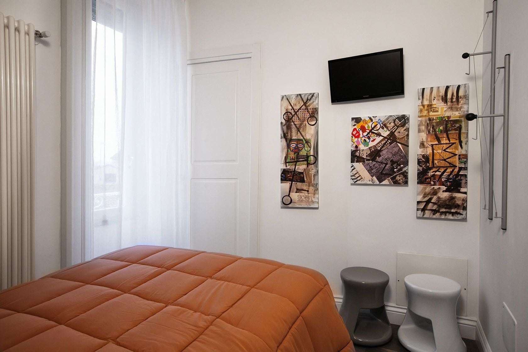 Un dormitorio con cama, televisor y arte abstracto en la pared.