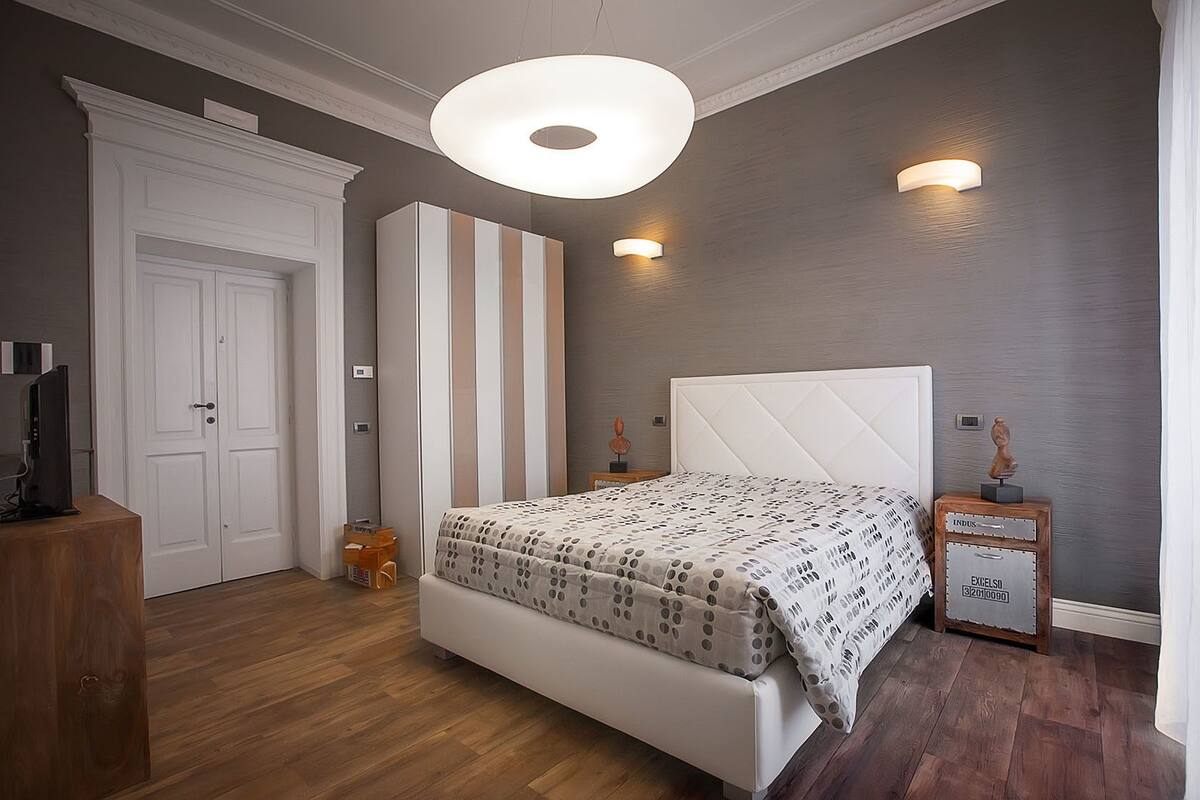 A bedroom with a bed, a wardrobe, a desk, and a nightstand.
