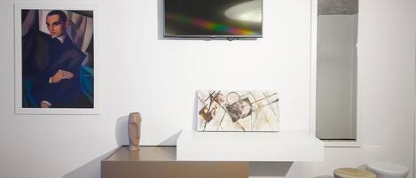 A minimalist art gallery with a modern sculpture, abstract paintings, and a large mirror.
